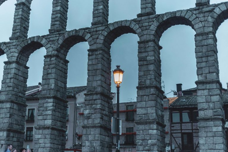 Edificio antiguo de piedra con arcos y una farola en una calle histórica